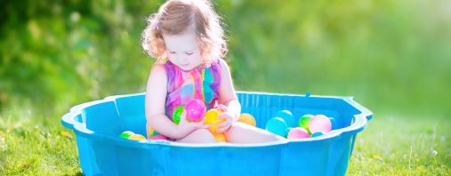 Toddler girl playing wil balls in the garden